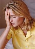 Woman holding her head while suffering from debilitating chronic migraine pain